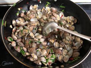 放入过凉的花蛤，少量料酒翻炒均匀。