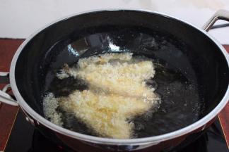 接着继续放鱼块，鱼块炸至微黄翻转，改为中火继续炸至金黄色，