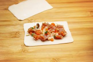 云吞皮擀薄，云吞皮本身很薄，再次擀薄，放入拌均好的磷虾肉馅；