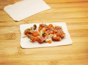 云吞皮擀薄，云吞皮本身很薄，再次擀薄，放入拌均好的磷虾肉馅；