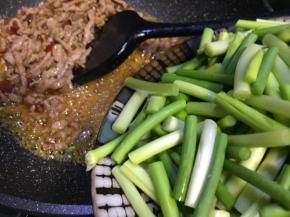 把肉推至一边，倒入蒜苔，用油料炒香