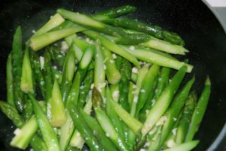 蒜末炒出香味后，加入芦笋，大火继续翻炒一分钟。