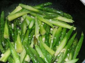 蒜末炒出香味后，加入芦笋，大火继续翻炒一分钟。