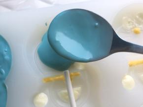 蓝色巧克力币融化后，倒入模具进行最后一步填充，另一只手固定纸棒