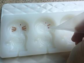 叮当猫的眼睛和胡须比较细，可以用裱花袋的尖尖角或者牙签沾巧克力进行描绘填充