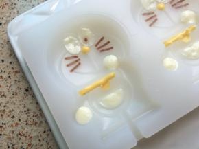 白色巧克力填入眼睛，手和口袋，特别要注意眼睛不能完全盖住，所有的细节部分不满意的可以用牙签去修改