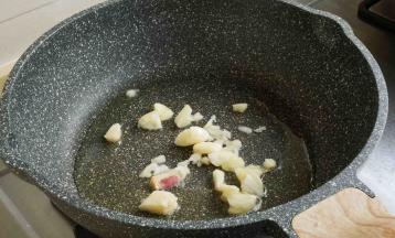 锅中油热，加入蒜瓣碎爆香