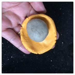 芋泥12克搓圆，南瓜泥面团20克，压扁，包入芋泥，搓圆。压扁一点。