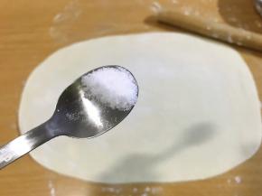 撒半勺盐，用手摸匀，轻轻把盐拍进面饼里。
