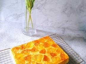 将蛋糕从烤盘中取出倒扣在晾网上，撕掉油纸，稍冷却即可切块享用