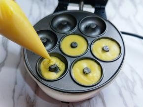 之后将裱花袋剪个很小的小口，将甜甜面糊挤入华夫饼机器模具中。