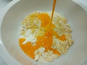 再一点点加入鸡蛋液，一边拌一边加，加好后，戴一次性手套，用手给面粉揉成团，揉均匀