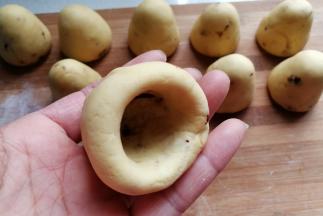 再继续用大拇指旋转着把四周捏薄，边捏边向上顶一下，让它形成一个自然的窝头形状