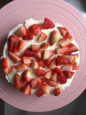 取一片蛋糕片，先抹一层淡奶油，在上面摆上草莓块儿