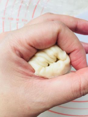 将油酥球包裹在油皮里面，利用手部虎口位置收口。因为油皮的延展性很好，不需要把油皮的圆形弄的太大。边收边推，就可以轻松收口。收好口后，盖保鲜膜松弛15分钟