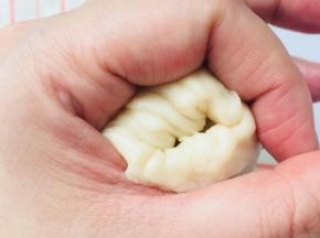 将油酥球包裹在油皮里面，利用手部虎口位置收口。因为油皮的延展性很好，不需要把油皮的圆形弄的太大。边收边推，就可以轻松收口。收好口后，盖保鲜膜松弛15分钟
