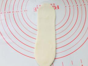 取一个面团卷，有螺旋开口的位置朝上下，侧面收口放于底部，按扁擀长。同样力度不可太大