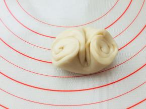 去一个面团，螺旋开口朝两头，在中心位置按压一下，将两头螺旋位置往中间收，边收边按扁。擀成圆形。