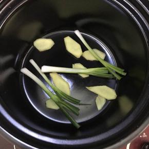 将砂锅放上煤气炉上，小火预热，放入葱段、姜片。