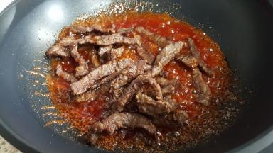 倒入炸好的里脊条迅速的煸炒，使每个里脊条上都裹满着酱汁。