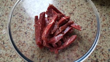 将切好的牛里脊放在容器中，加入一点点料酒和少许食盐调一个底味。