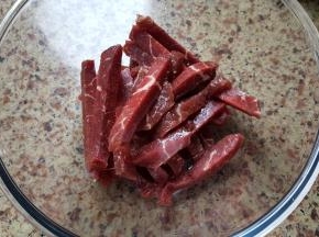将切好的牛里脊放在容器中，加入一点点料酒和少许食盐调一个底味。