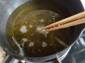 小的奶锅中放入足够多的植物油，中火加热至有面糊的筷子放入可以迅速的冒起泡泡。