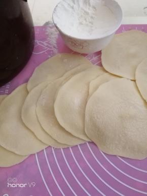 剂子用手掌心按压一下，擀成边薄内厚的皮子