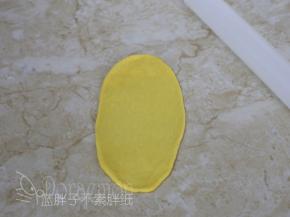 松弛好的面团压扁，用擀面杖擀成椭圆形。