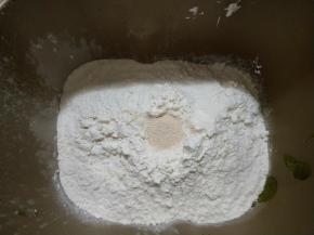 对角放盐和糖，再放入高筋面粉，中间挖个洞放入酵母。