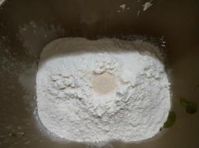 对角放盐和糖，再放入高筋面粉，中间挖个洞放入酵母。