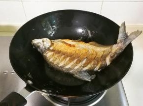 调小火放入提前擦干水分的鳊鱼，中火煎黄两面