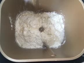 面包桶内加入低筋面粉跟一小撮盐，加清水启动揉面程序，将材料揉成面团