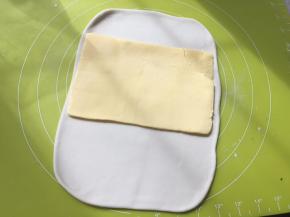 冰箱取出冷冻的黄油片，裁掉保鲜袋，铺在面片中间