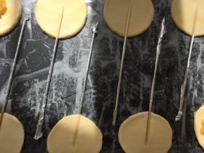 在圆片中间压上包裹着锡纸的小棍，锡纸调整在面片的边缘