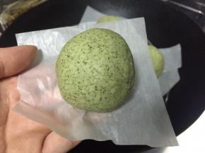 将豆沙蓉包裹着肉松，再将艾草团搓圆按扁揉成小窝窝，像包包子一样借助手掌虎口慢慢推包入收口朝下