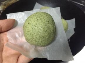 将豆沙蓉包裹着肉松，再将艾草团搓圆按扁揉成小窝窝，像包包子一样借助手掌虎口慢慢推包入收口朝下