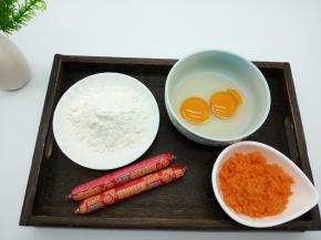 先来准备一些摊饼所需要的食材，鸡蛋2个，火腿肠2根，中筋面粉50克，胡萝卜泥