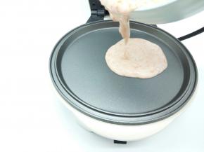 煎好火腿肠，用厨房纸巾轻轻一擦，烤盘瞬间就很干净，都不用洗，刷一点油，盛一勺面糊放入中间位置（要用华夫机的平底烤盘）用推面糊棒给推平，盖上盖子，焖1分钟