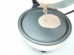 煎好火腿肠，用厨房纸巾轻轻一擦，烤盘瞬间就很干净，都不用洗，刷一点油，盛一勺面糊放入中间位置（要用华夫机的平底烤盘）用推面糊棒给推平，盖上盖子，焖1分钟