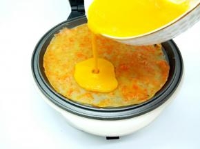 等饼皮四周翘起，倒入适量的鸡蛋液，一样给摊平整，再盖上盖子焖一分钟