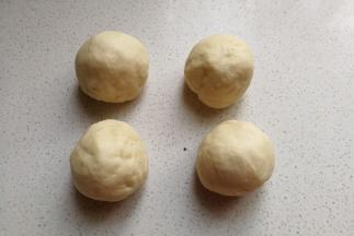 再把揉好的面团取出来，分成均匀的四份滚圆