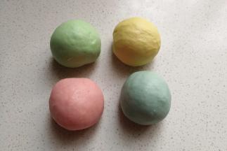 四份小面团中分别加入四种颜色的食用色素，揉均匀后并滚圆，再摆入烤盘中盖上保鲜膜放温暖处发酵