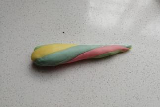 再把四种颜色的面团扭转着滚圆搓紧，搓成更长的彩色水滴状