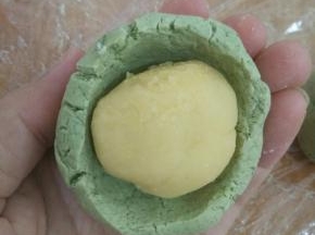 取个艾叶面团，用拇指在中间慢慢转出一个洞，放入绿豆馅。