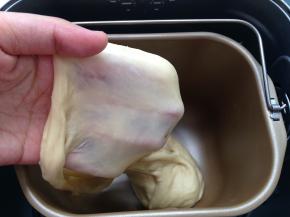 继续启动面包机和面功能，揉至面团能拉出薄膜