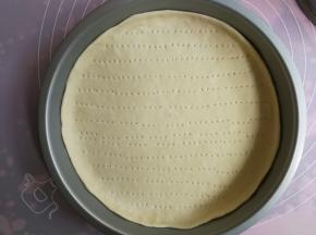 放入9寸披萨盘里，用手整理好边缘，使面片与披萨盘贴合平整，然后用叉子在面片上叉出小洞，以免烘烤时鼓起