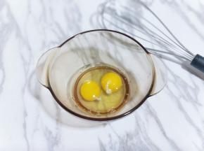 首先把鸡蛋敲入大口器具中，用手动打蛋器将鸡蛋打散。(我选用的草鸡蛋，比较小，所以我用了两只，约65g)