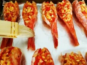 烤盘垫锡纸，预热烤箱，220度十分钟左右，把爆香的蒜泥辣椒碎填入虾背里面，用刷子在虾子外面刷一层植物油