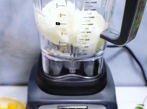 将酸奶冰块用勺子敲碎后，放入搅拌杯里。

